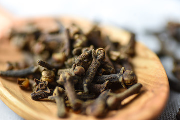 Cloves on a wooden spoon, old wooden background, selective focus