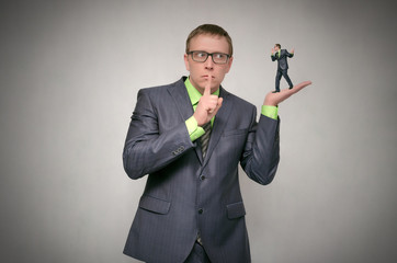Curious and amazed business man listens attentively other person on his palm hand isolated on gray...