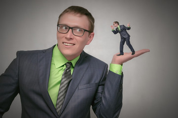 Curious and amazed business man listens attentively other person on his palm hand isolated on gray...