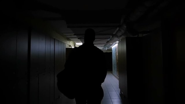 Slow motion mideo of man going to gym in the dark corridor