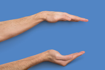 Male hands measuring invisible item at beige background