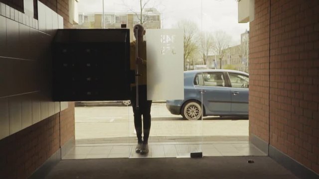 Happy woman using intercom at building entrance 