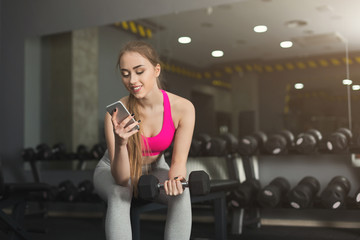 Fototapeta na wymiar Young girl using mobile phone at gym
