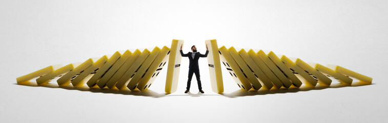 Fototapeta The man stops the falling dominoes. Concept of crisis management. obraz