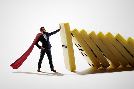 The man stops the falling dominoes. Concept of crisis management.