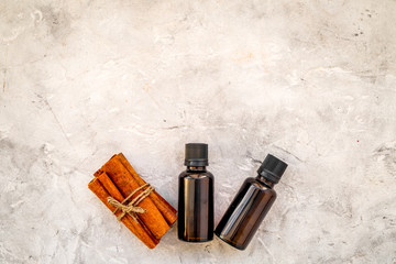 Cinnamon oil for cooking, aromatheraphy, skin care. Bottles near cinnamon sticks on grey background space for text