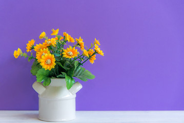 Purple wall with yellow flower on shelf white wood, copy space for text. Still life Concept