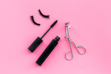 Cosmetics and tools for voluminous lashes. Mascara, false eyelashes, eyelash curler on pink background top view copy space