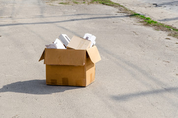 cardboard box with office supplies on the road on the asphalt. Dismissal from work, eviction from the apartment