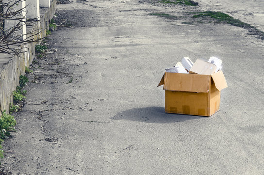 cardboard box with office supplies on the road on the asphalt. Dismissal from work, eviction from the apartment