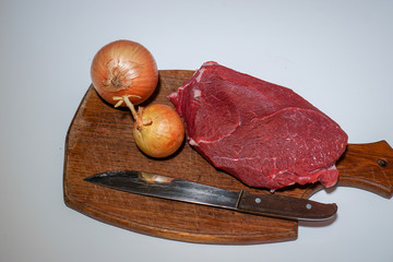 Beef meat fresh, on a board with a bow and knife on a white background