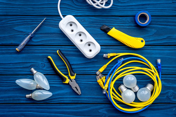 Naklejka premium Electrical repair. Bulbs, socket outlet, cabel, screwdriver, pilers on blue wooden background top view