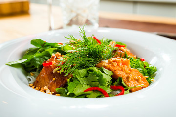 Fish salad dressed with sauce and herbs on the table to wine