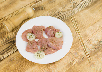Raw chicken fillet sprinkled with spices on a wooden background. Preparation for cooking.