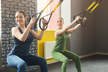 Women performing TRX suspension training in gym