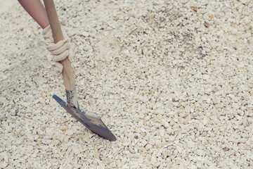 Female diggings stone for the cement with shovel. Close-up. Concept