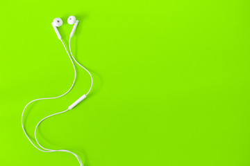 Top view of White Earphones on green background. Copy space. Music is my life concept