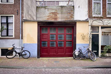 Fototapeta na wymiar a vibrant red garage door on an old building with bicycles parked on the street.