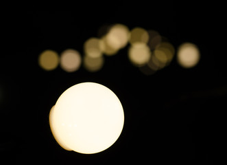 Soft bokeh background.  Garland of electric lights. Place to add text. Blurry abstraction. Black & white. Dark night. Festive party in city. Soft focus effect.