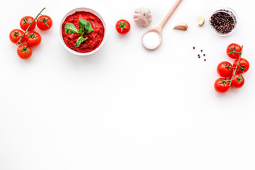 Ingredients for tomato sauce. Cherry tomatoes, garlic, green basil, black pepper, salt in spoon on white background top view copy space