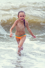 Child girl in the waves at sea.