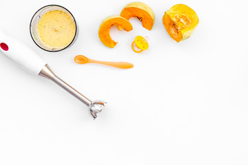 Make baby food at home. Puree with pumpkin near immersion blender and pacifier on white background top view copy space