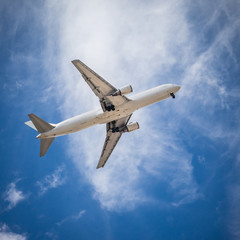 Passenger carrier airplane flying on the blue cloudy sky.