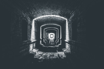Ruined brick underground tunnel or corridor and light in end, way to hope concept, black and white...