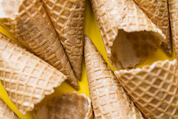 Empty waffle wafer ice cream cone on a bright yellow background