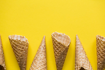 Empty waffle wafer ice cream cone on a bright yellow background