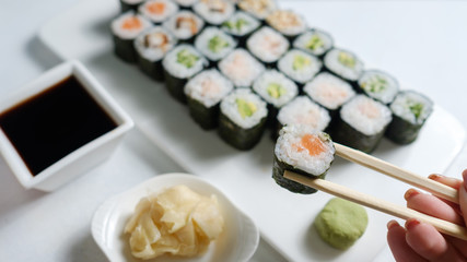 homemade sushi assortment. Asian cuisine and Japanese food concept. Woman tasting rolls with chopsticks