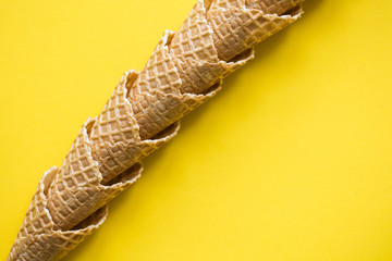 Empty waffle wafer ice cream cone on a bright yellow background