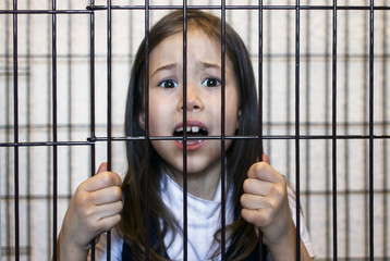 The little girl is locked in an iron cage. Restriction of the rights of the child. Child crime