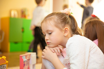Obraz na płótnie Canvas Portrait of sad blond little girl sitting in kindergarten