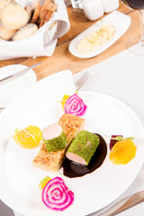 Roast pork tenderloin with crispy potato bread, marinated beetroots and green pepper sauce served in a restaurant