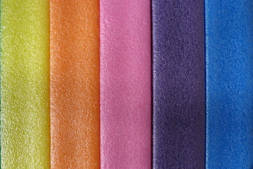 bright multicolored stripes of plastic pink yellow orange green foam rubber close-up background