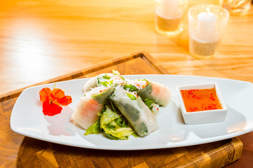 Oriental Vietnamese dish, spring rolls with cabbage and rice pasta on a plate with vegetables, close-up