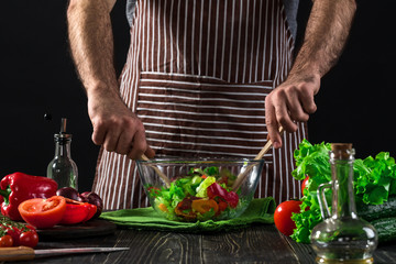 Man preparing salad with fresh vegetables on a wooden table. Cooking tasty and healthy food