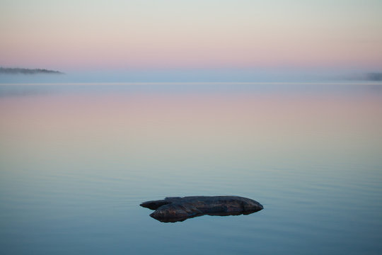 Misty morning fog over the calm karelian lake