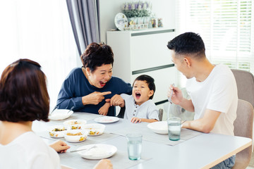 Happy Asian extended family having dinner at home full of laughter and happiness