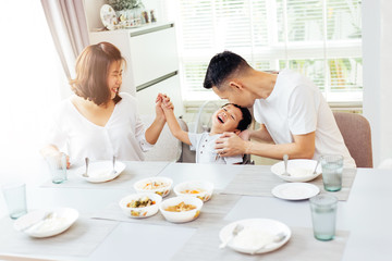 Happy Asian family of father, mother and son playing and laughing while having dinner
