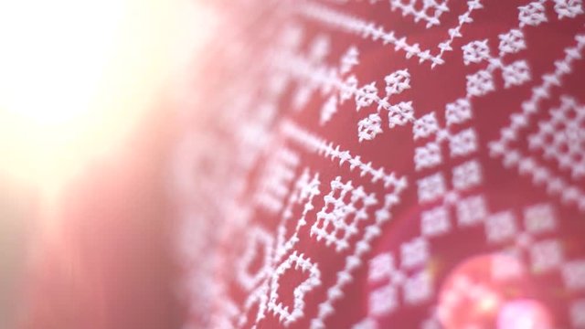 Red texture cloth embroidered with thick white thread in warm sunlight, close-up. Vyshyvanka, traditional folk ethnic ukrainian national costume. Eastern European hand embroidered shirt sorochka.