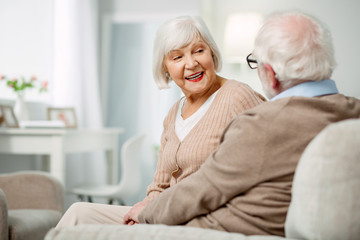 Pleasant communication. Cheerful nice aged woman looking at her husband while talking to him