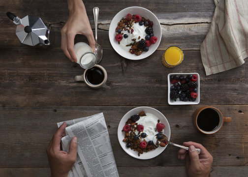 Still Life Of Couple At Breakfast Shot From Overhead, Woman Pouring Cream Into Coffee