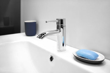 Luxury modern style faucet mixer on a white sink in a beautiful gray and white bathroom
