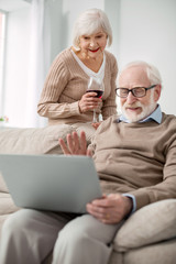 Fototapeta premium Distance communication. Positive nice aged couple looking at the laptop screen while making a video call