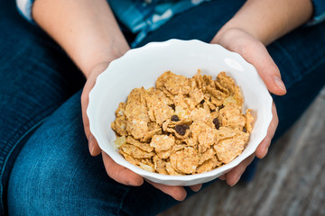 Girl with a plate of cereal. Flakes from whole wheat with dried fruits. Healthy eating concept. A girl in jeans and a plaid shirt. Proper nutrition. Healthy food.