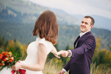 Walking with a mountain lawn. Carpathian Mountains in the background. Newlyweds on the wedding day