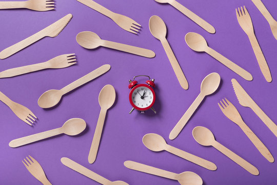 Many wooden spoons and forks on purple background, top view