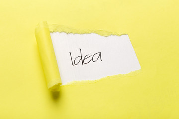 Idea inscription showing up behind yellow torn paper